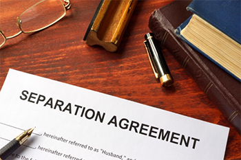 Document on desk reading separation agreement with pen and books