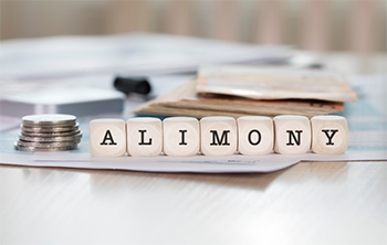 Wooden blocks spelling out alimony next to coins