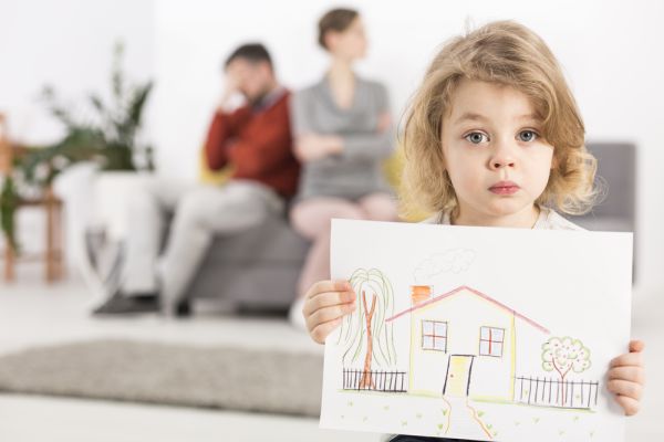 Little girl holding her drawing of a home